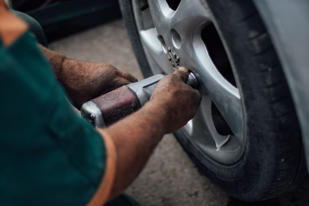 Technician using an impact wrench on a vehicle wheel